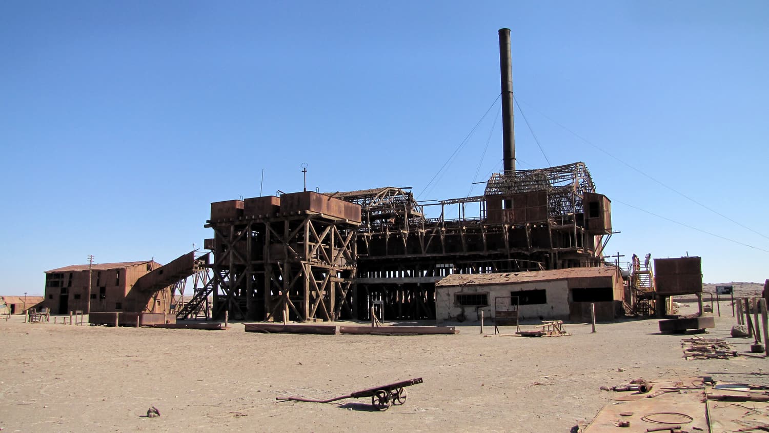 The timber-and-iron leaching plant and tall chimney of the Santa Laura saltpeter works in the Atacama Desert