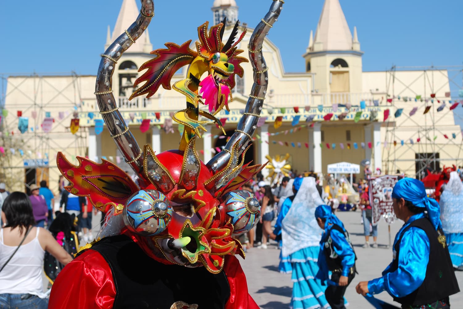 A dancer in a horned diablada mask in front of the sanctuary during the Fiesta de La Tirana