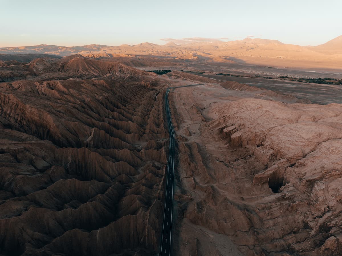 A road running between eroded desert ridges in the Atacama