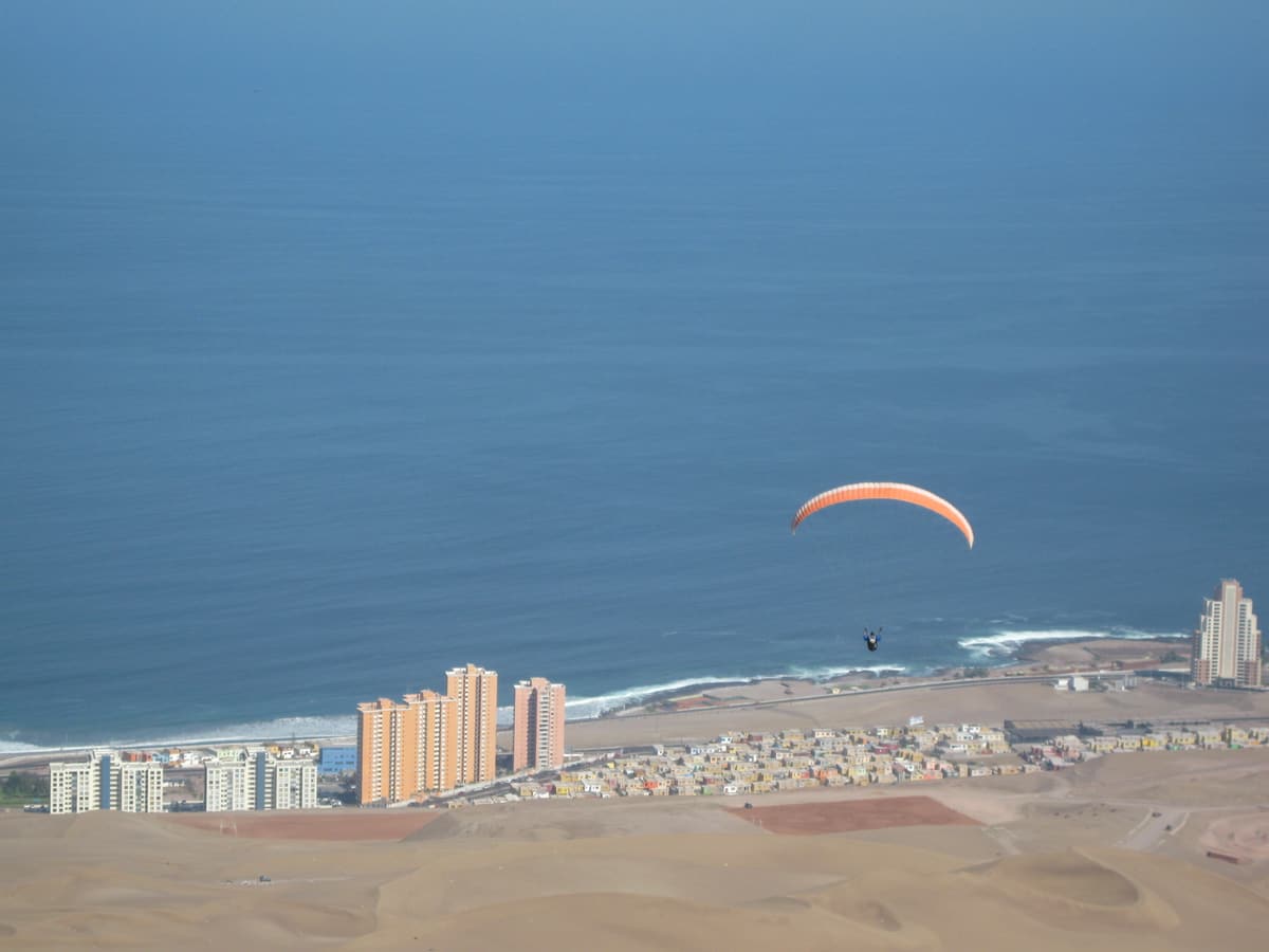 A paraglider high above the city of Iquique and the Pacific coast